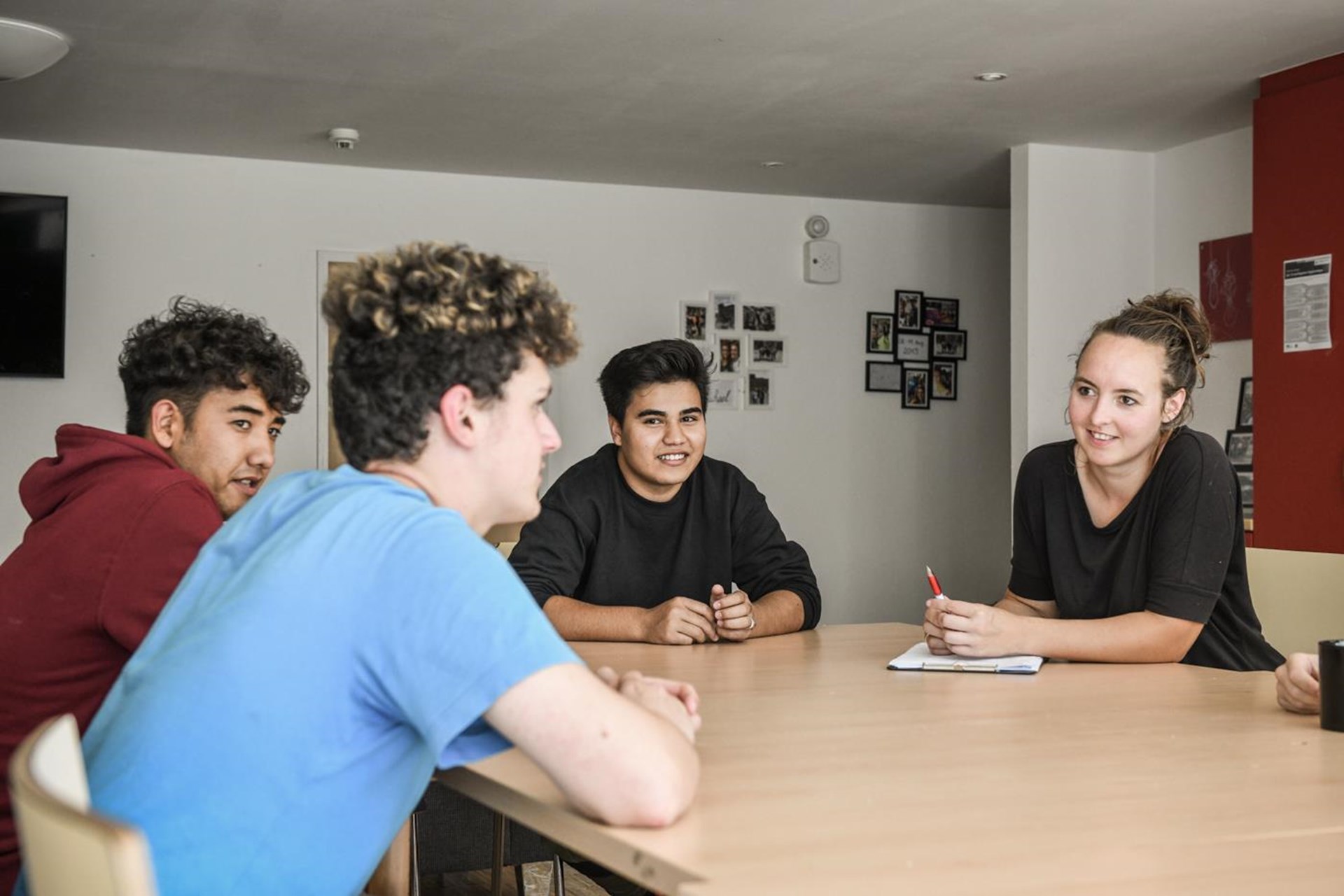 Junge Menschen sitzen am Tisch und lachen