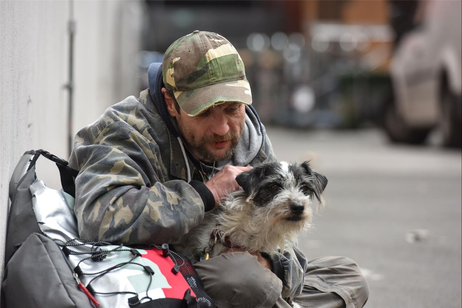 obdachloser Mann streichelt seinen Hund