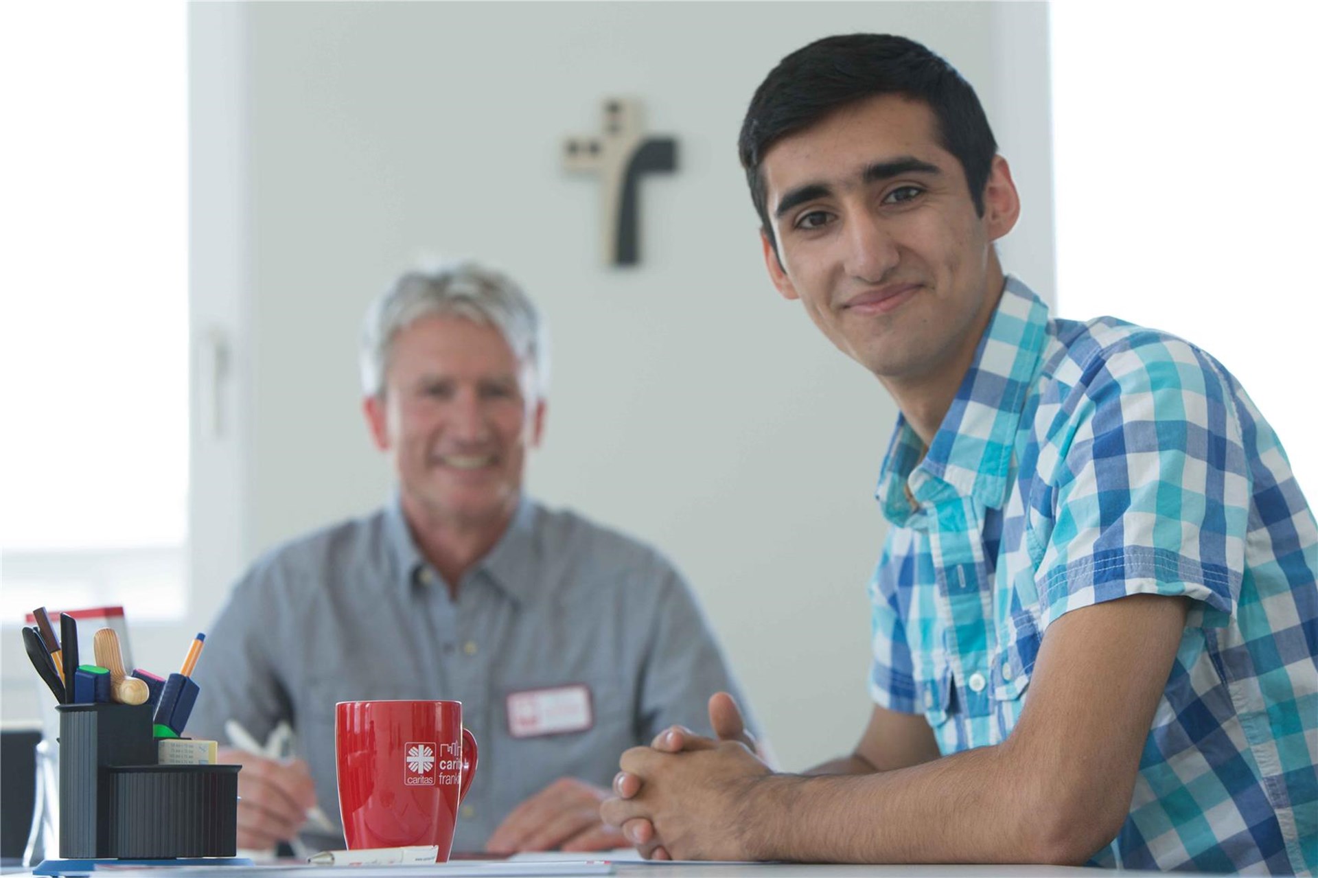 Jüngerer Migrant  mit einem Berater bei der Caritas