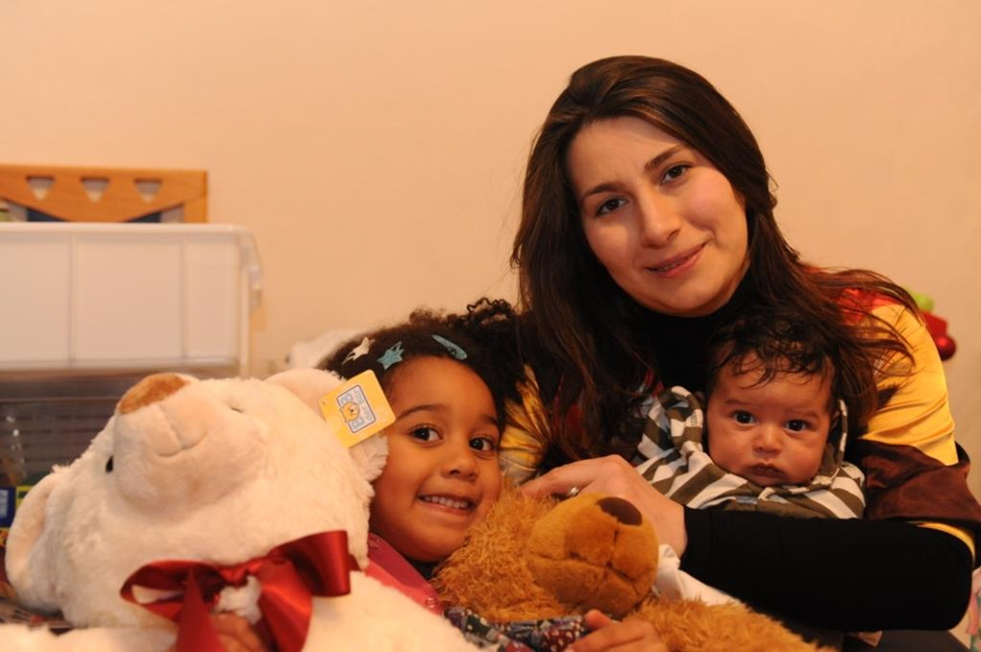 Mutter sitzt mit Baby und kleiner Tochter auf dem Sofa